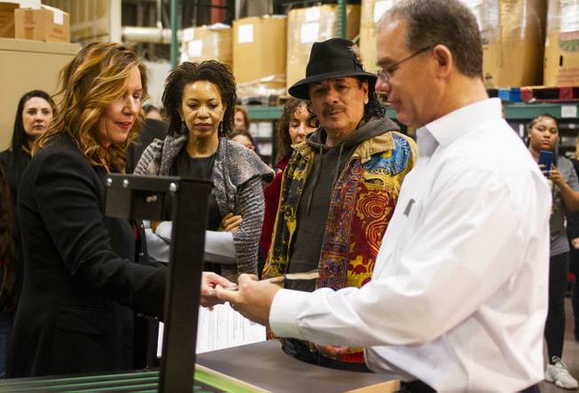 Executive Director/Co-Founder Lisa Habighorst, left, and Director of Operations David Ortlipp, right, of Spread the Word Nevada demo a book sorting machine for Carlos Santana, center right, and his wife Cindy Blackman, center left, during a tour of the Spread the Word facilities at their warehouse in Henderson, NV, Thursday, Jan. 17, 2019. The Milagro Foundation made a donation to Spread the Word, which will provide about 15,000 books to 57 schools across Southern Nevada.