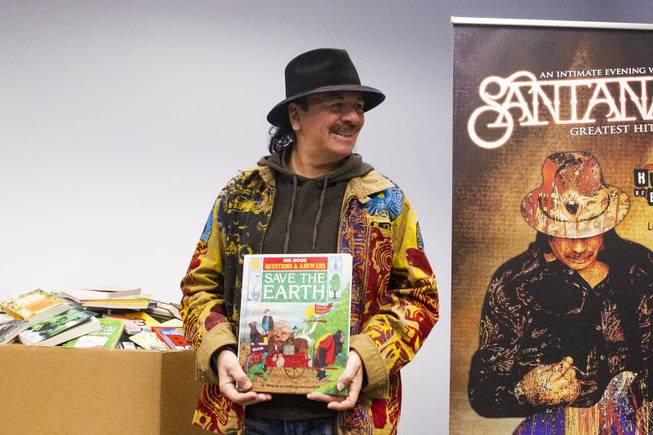 Carlos Santana poses for a photo with a donated book during a tour by him, his wife Cindy Blackman, and his Milagro Foundation staff at the Spread the Word Nevada offices and warehouse in Henderson, NV, Thursday, Jan. 17, 2019. The Milagro Foundation made a donation to Spread the Word, which will provide about 15,000 books to 57 schools across Southern Nevada.