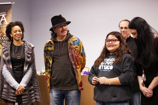 Carlos Santana, center left, and his wife Cindy Blackman, left, look on as Maya, a CC Ronnow Elementary School student, center right, explains one of her school's reading programs during a tour at the Spread the Word Nevada offices and warehouse in Henderson, NV, Thursday, Jan. 17, 2019. Santana's Milagro Foundation made a donation to Spread the Word, which will provide about 15,000 books to 57 schools across Southern Nevada including lower socioeconomic schools like CC Ronnow Elementary School.