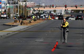 A member of Metro Police Department's fatal detail takes measurements at a fatal auto -pedestrian accident on Alta and Decatur Boulevard Thursday, Feb. 7, 2018.