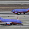 In this Sept. 4, 2013, file photo, a Southwest Airlines Boeing 737 takes off, rear, as another taxis in the north runway complex at Los Angeles International Airport (LAX).
