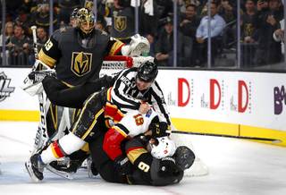 An official falls to the ice with Calgary Flames left wing Matthew Tkachuk (19) and Vegas Golden Knights defenseman Colin Miller (6) during a fight near the end of the second period at T-Mobile Arena Wednesday, April 6, 2019. Vegas Golden Knights goaltender Marc-Andre Fleury (29) looks on at left.
