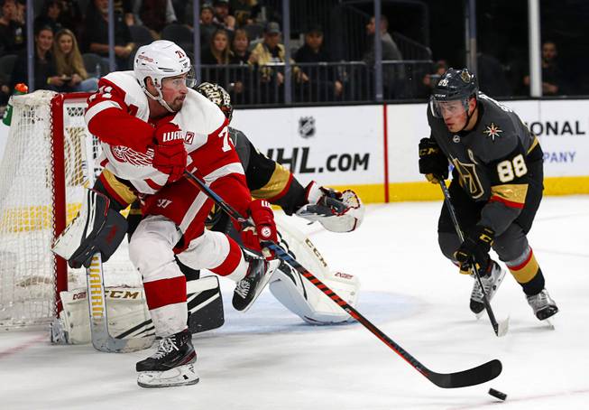 Detroit Red Wings center Dylan Larkin (71) passes to teammate Anthony Mantha, not pictured, who scores in  overtime for a 3-2 win over the Vegas Golden Knights at T-Mobile Arena Saturday, March 23, 2019. Vegas Golden Knights defenseman Nate Schmidt (88) defends at right. 