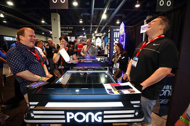 Canadians Jon McCartney, left, and Robert Ward play a mechanical Atari Pong Table game at the Unis Technology booth during the Nightclub & Bar Convention and Trade Show at the Las Vegas Convention Center Tuesday, March 26, 2019. The table uses magnetic technology to recreate the traditional video game.