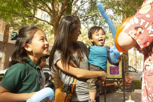 Terumi Wright with her two children Hana, 8, left and Noa, 2, right, react to a balloon artist at work during Ben & Jerry's Free Cone day at The District at Green Valley Ranch Tuesday, April 9, 2019. All donations benefit the Court Appointed Special Advocate (CASA) Foundationa nonprofit group supporting children in foster care.