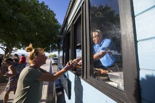 Andy Ross hands food to Christina Young from the Goodness Gracious Ministries food truck in Henderson on Monday, May 6, 2019.