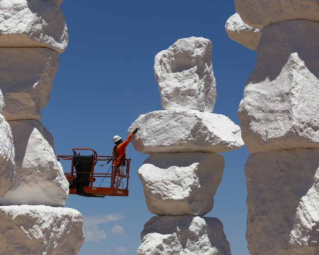 A worker paints a stone at Seven Magic Mountains during ...