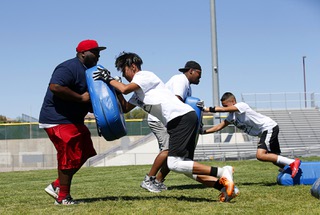 Coaches Teddy Booker, left, and Damon Mattison hold pads in a lineman station during the 4th Annual Brandon Marshall Youth Football Camp at Canyon Springs High School Saturday, June 8, 2019. Marshall, a Cimarron-Memorial High School alumni, is a linebacker for the Oakland Raiders.