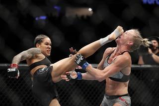 UFC bantamweight and featherweight champion Amanda Nunes of Brazil lands a kick on Holly Holms that knocks her to the mat in the first round of their bantamweight title fight during UFC 239 at T-Mobile Arena Saturday, July 6, 2019. 