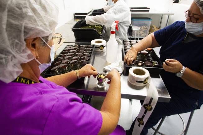 Employees apply Reina brand product labels by hand during a tour at the Premium Produce marijuana cultivation and production facility Friday, July 26, 2019.