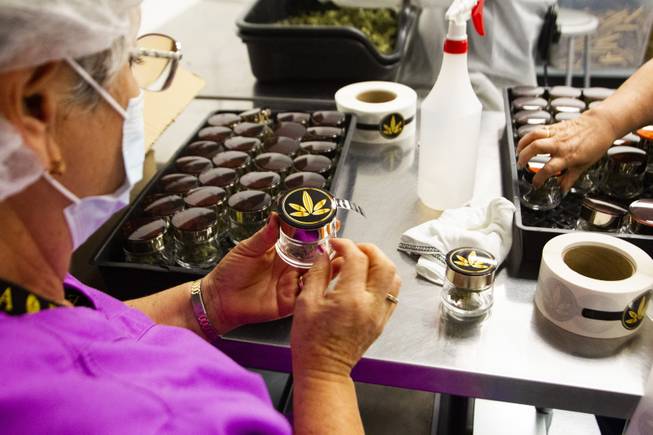 Employees apply Reina brand product labels at the Premium Produce marijuana cultivation and production facility Friday, July 26, 2019.