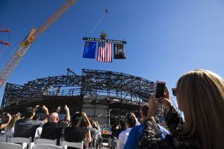Attendees watch as the final iron beam is lowered during a topping off ceremony at the Raiders' stadium, Monday, Aug. 5, 2019.