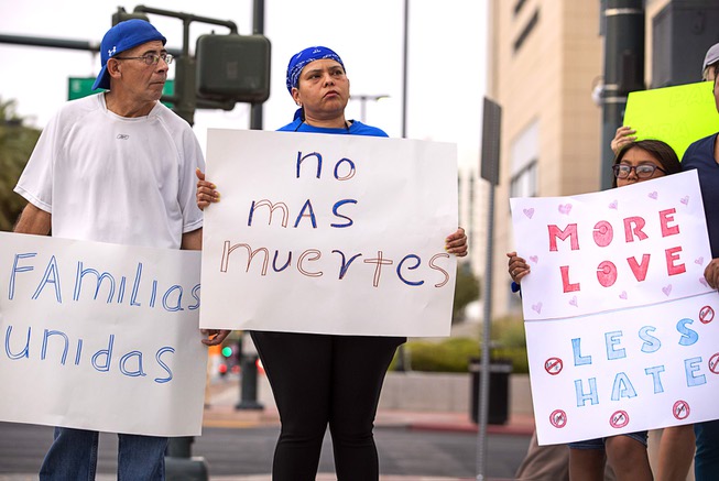 Francis Garcia, center, holds a sign in Spanish that reads ...