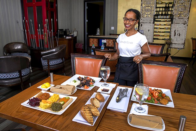 Co-owner Mini Yohannes poses behind an Ethiopian meal at NU ...