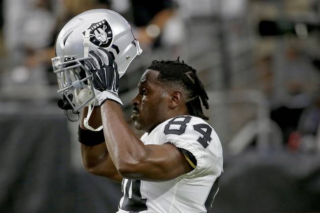 In this Aug. 15, 2019, file photo, Oakland Raiders wide receiver Antonio Brown (84) puts on his helmet prior to the team's NFL football game against the Arizona Cardinals in Glendale, Ariz.