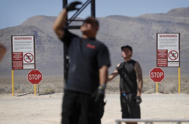 Workers erect a stage near replica Area 51 gate signs ...