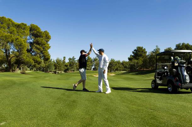 Forecaddie James Newman hi-fives reporter Justin Emerson during a round of golf at the newly re-opened Wynn Golf Club, Wed. Nov. 6, 2019.  