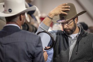 A customer checks out the look of a new hat in the Best Hat Store booth at Cowboy Christmas in the Las Vegas Convention Center South Halls on Thursday, Dec. 5 2019.
