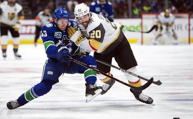 Vancouver Canucks defenseman Quinn Hughes (43) vies for control of the puck with Vegas Golden Knights center Chandler Stephenson (20) during the third period of an NHL hockey game Thursday, Dec. 19, 2019, in British Columbia. 