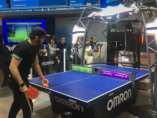 A trade show attendee plays against Forpheus, a table tennis robot tutor, at CES Tuesday, Jan. 7, 2020.