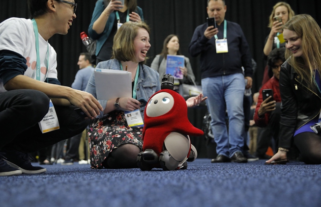 People interact with a Lovot robot during CES Unveiled before ...