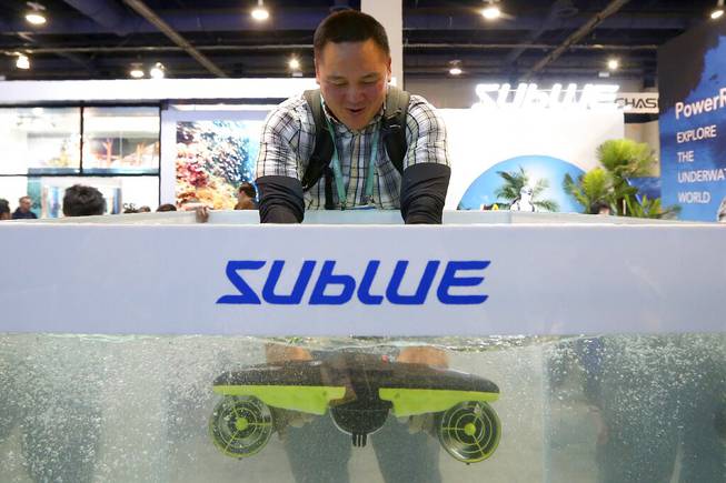 Hendrick Tran test the Sublue Seabow in a water tank at the Sublue booth during the CES tech show Wednesday, Jan. 8, 2020, in Las Vegas. 