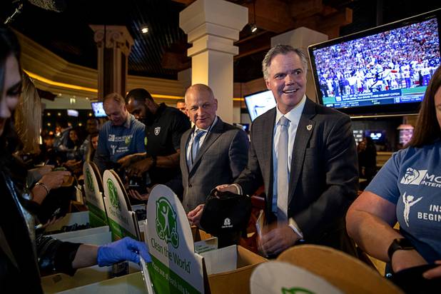 Marc Badain, center, president of the Las Vegas Raiders, and Jim Murren, right, chairman and CEO of MGM Resorts International, help package hygiene kits for veterans before  a news conference at Mandalay Bay Thursday, Jan. 23, 2020. At far left (black shirt) is Raiders alumni Darren McFadden.