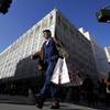 In this Nov. 29, 2019, file photo, man carries shopping bags across the street from a Macy's store in San Francisco.