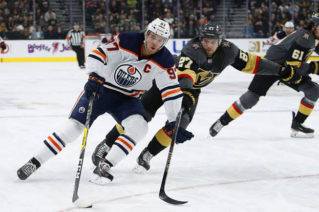 Edmonton Oilers center Connor McDavid (97) skates around Vegas Golden Knights defenseman Shea Theodore (27) during the first period of an NHL hockey game Wednesday, Feb. 26, 2020, in Las Vegas.