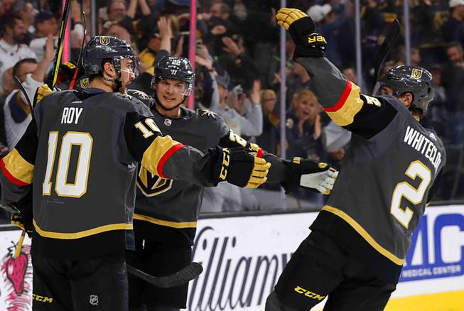 Vegas Golden Knights center Nicholas Roy (10) celebrates with Nick Holden (22) and Zach Whitecloud (2) after scoring during the first period of an NHL hockey game against the Buffalo Sabres at T-Mobile Arena in Las Vegas Friday, Feb. 28, 2020. 