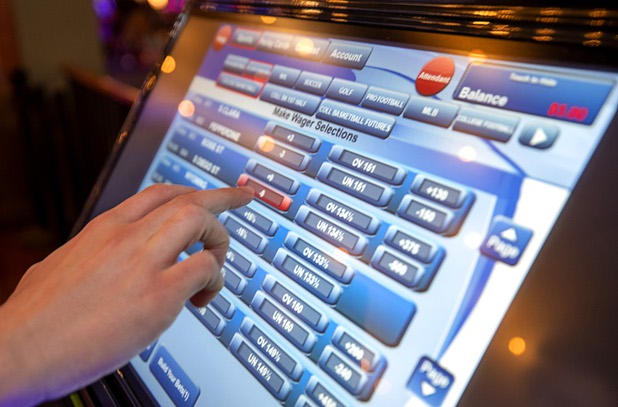 A journalist makes a bet on college basketball using a self-service betting kiosk in the BetMGM sports book at the Park MGM Friday, March 6, 2020.