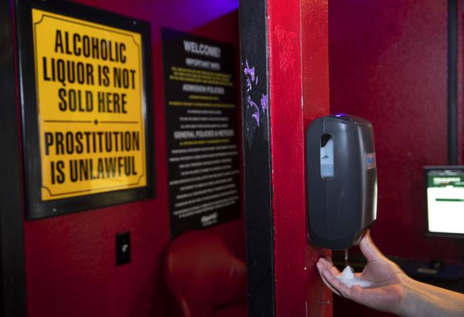 Manager Johnny T. gets hand sanitizer from a dispenser in the lobby of the Little Darlings adult entertainment club on Western Avenue Thursday, March 19, 2020.