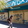 A man walks past a boarded up business on Main Street, downtown, Tuesday, March 24, 2020.