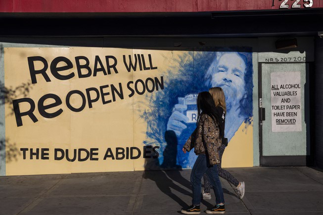 People walk past a the boarded up painted exterior of ...