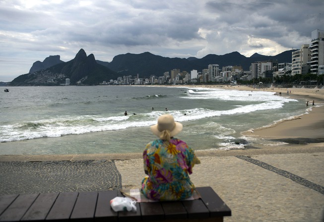 An elderly woman watches Arpoador beach in Rio de Janeiro, ...