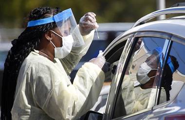 A health care worker with the UNLV School of Medicine tests a patient for the coronavirus at a drive-thru testing site Thursday, March 26,&nbsp;2020. 