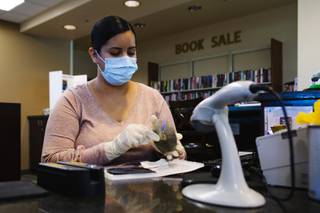 Library assistant Ericha Camacho disinfects a DVD at Alexander Library in North Las Vegas, Wednesday, April 29, 2020.