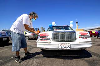 Eddy Ramos decorates a stretched 1990 Lincoln Town Car before a caravan to a drive-in rally at the Sawyer State Building on International Workers' Day Friday, May 1, 2020. Demonstrators asked for immigrant workers and families to be included in federal assistance during the coronavirus outbreak.