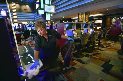 Antonia Garcia cleans slot machines at the Planet Hollywood in Las Vegas, March 18, 2020. When shuttered casinos reopen in Nevada, fewer patrons will be allowed in, nightclubs will remain closed, convention groups will be limited and gamblers will have to keep safe distances apart.