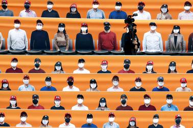 A TV cameraman walks through the spectators' seats which are covered with pictures of fans, before the start of a regular season baseball game between Hanwha Eagles and SK Wyverns in Incheon, South Korea, Tuesday, May 5, 2020. South Korea's professional baseball league start its new season on May 5, initially without fans, following a postponement over the coronavirus. 