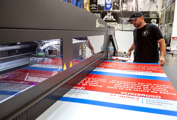 Press operator Tom DeJonge prints a COVID 19-related sign at Screaming Images Thursday, May 7, 2020. Screaming Images is a graphic design and installation firm.