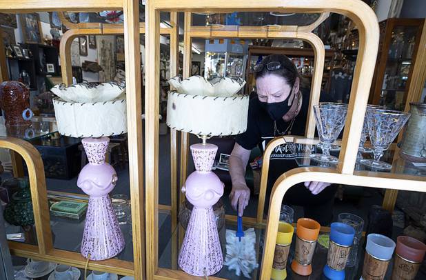 Cindy Myers dusts a shelf in Vintage Vegas on Main Street Saturday, May 9, 2020. Saturday was the first day restaurants, salons and other nonessential businesses were allowed to reopen after restrictions were imposed to help slow the spread of the new coronavirus.