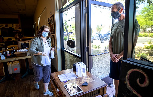 Owner Katalin Racz brings an order of hand sanitizer to Scott Freebairn at the Las Vegas Distillery in Henderson Tuesday, May 12, 2020. The distillery has switched from making distilled spirits to hand sanitizer in order to help in the fight against the novel coronavirus (COVID-19).