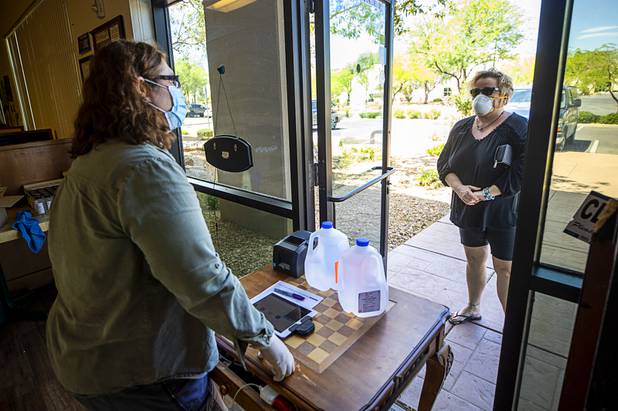 Owner Katalin Racz talks with Julia Willis-Leon as she p[icks up an order of hand sanitizer to Scott Freebairn at the Las Vegas Distillery in Henderson Tuesday, May 12, 2020. The distillery has switched from making distilled spirits to hand sanitizer in order to help in the fight against the novel coronavirus (COVID-19).