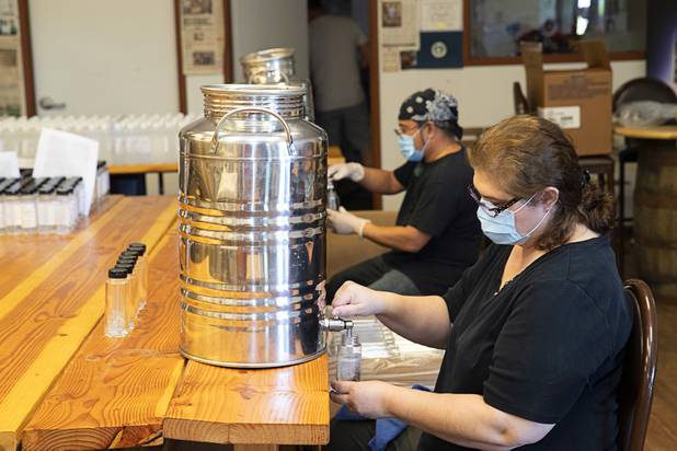 Owner Katalin Racz, foreground, and Julian Morales bottle hand sanitizer at the Las Vegas Distillery in Henderson Wednesday, May 13, 2020. The distillery has switched from making distilled spirits to hand sanitizer in order to help in the fight against the novel coronavirus (COVID-19).