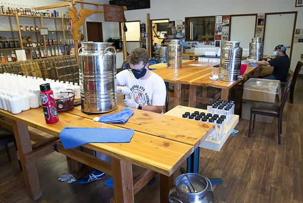Will Wood, left, and Julian Morales bottle hand sanitizer at the Las Vegas Distillery in Henderson Wednesday, May 13, 2020. The distillery has switched from making distilled spirits to hand sanitizer in order to help in the fight against the novel coronavirus (COVID-19).