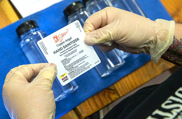 Claudia Morales attaches labels to bottles of hand sanitizer at the Las Vegas Distillery in Henderson Wednesday, May 13, 2020. The distillery has switched from making distilled spirits to hand sanitizer in order to help in the fight against the novel coronavirus (COVID-19).