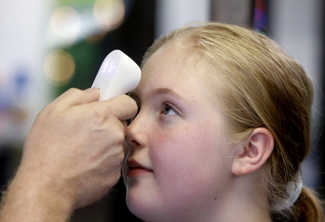 Kaiden Melton, 12, has her temperature taken during a daycare ...