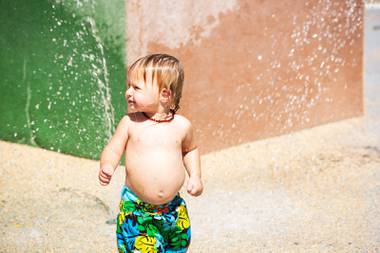 1-year-old Landon Lucas plays in the water at the splash pad in Mission Hills Park as it re-opens to the public, Friday May 29, 2020,