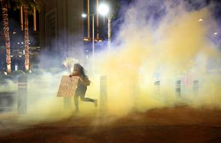 A protester runs through gas on the Las Vegas Strip Sunday, May 31, 2020, in Las Vegas, over the death of George Floyd, a black man who was in police custody in Minneapolis. Floyd died after being restrained by Minneapolis police officers on Memorial Day.